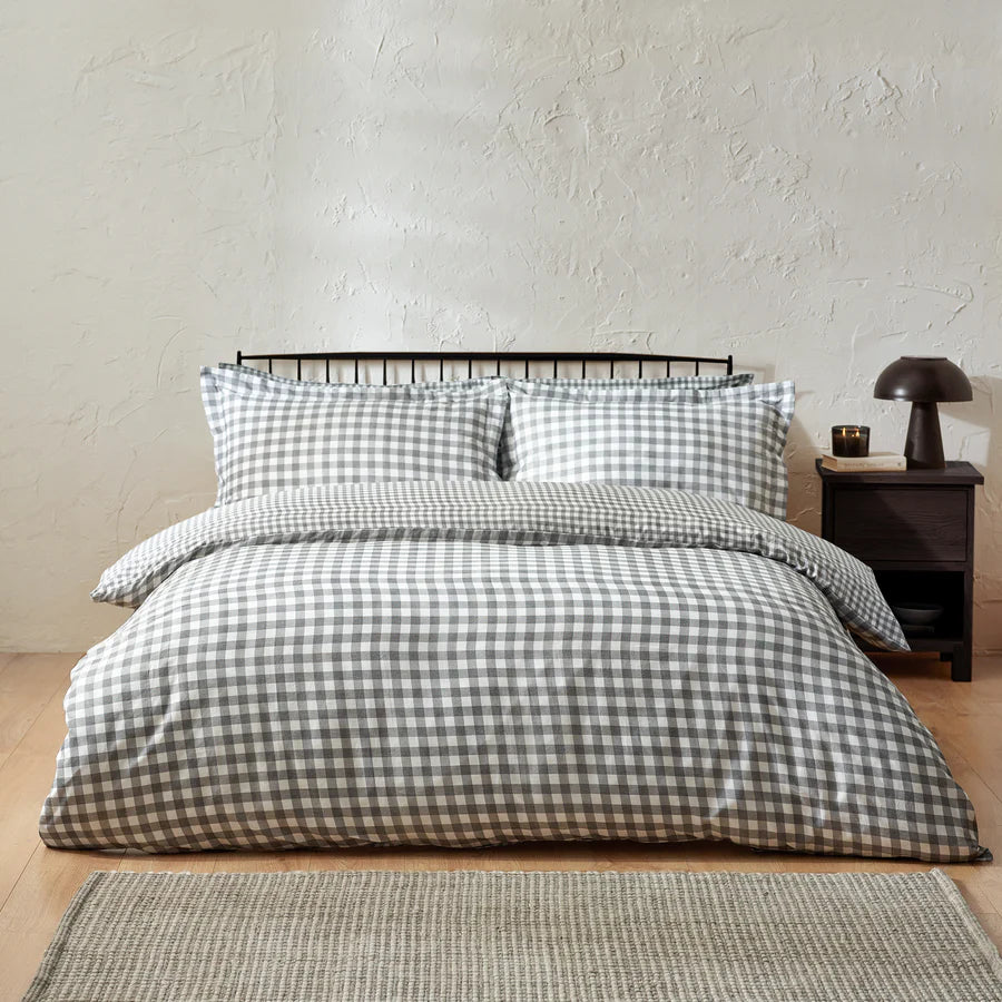 Grey gingham bedding set on bed with bedside table.