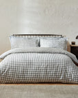 Grey gingham bedding set on bed with bedside table.