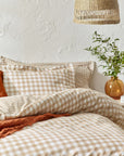 Ginger biscuit gingham bedding set on bed with cushion and throw folded.