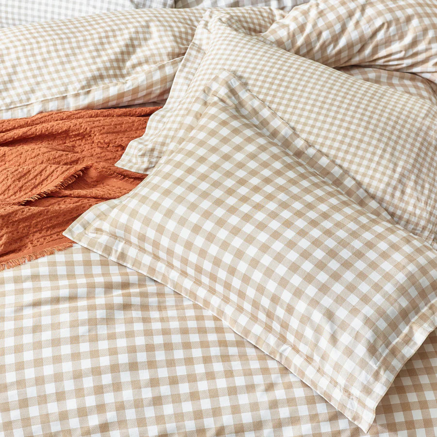 Close up of ginger biscuit gingham bedding set on bed with cushion and throw.