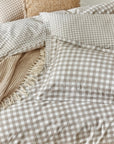 Close up of natural gingham bedding set on bed with cushion and throw.