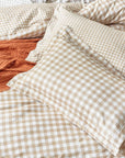 Close up of ginger biscuit gingham bedding set on bed with cushion and throw.