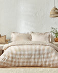 Ginger biscuit gingham bedding set on bed with bedside table and armchair.