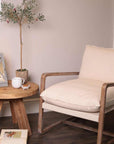 Wooden arm chair styled with coffee table with mug and biscuits and plant.