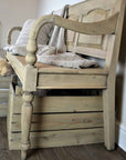 Vintage wooden bench with back with throw and cushion, and baskets underneath. Side view and close up of leg detailling.