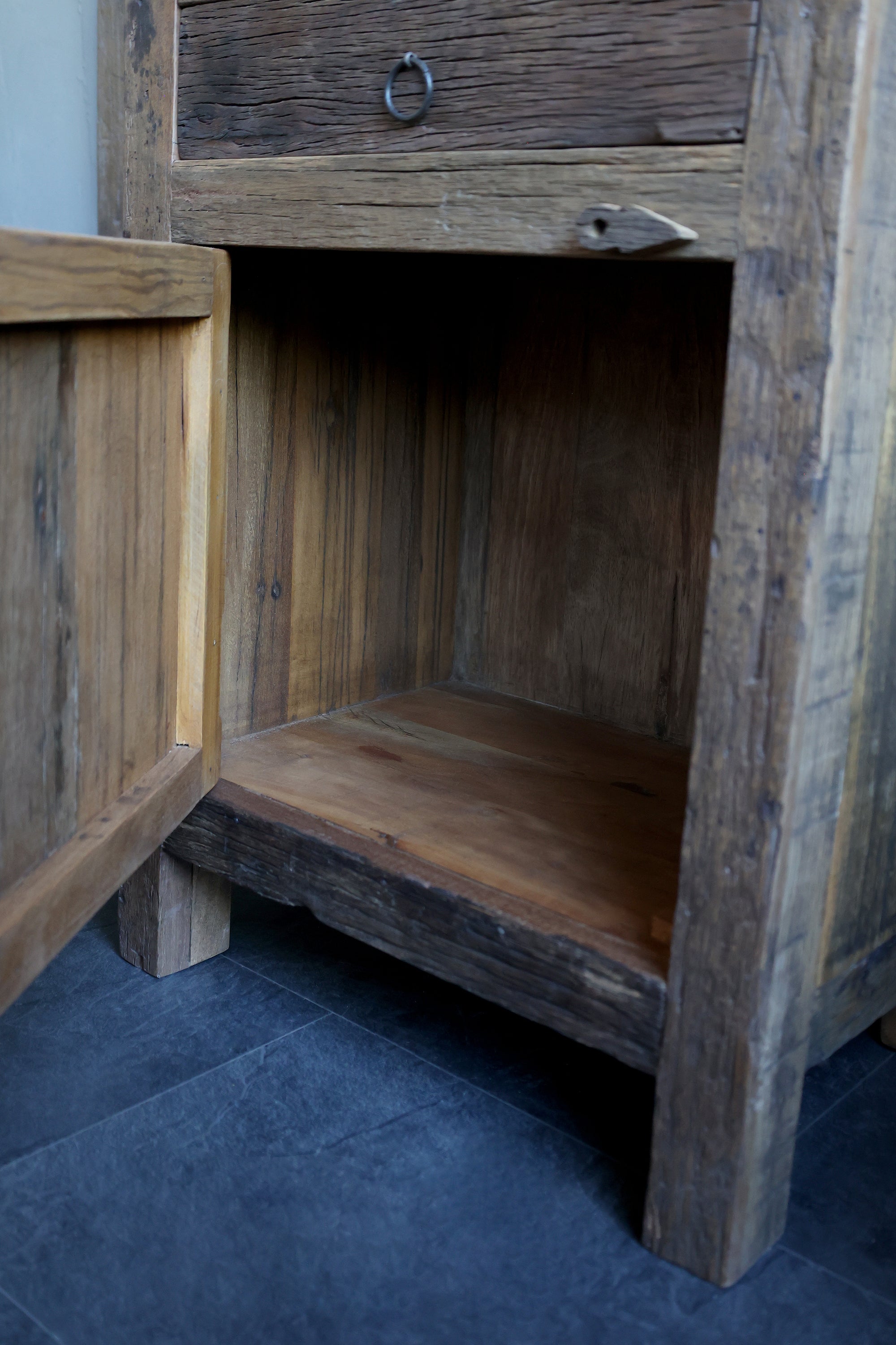 Reclaimed wooden cabinet with one drawer and one door open.