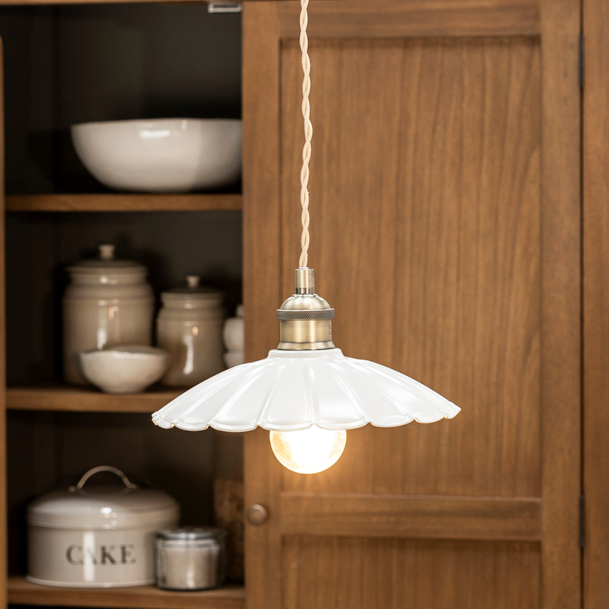 White fluted ceramic pendant light in wooden kitchen.