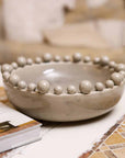 Grey bobble bowl on table with book.