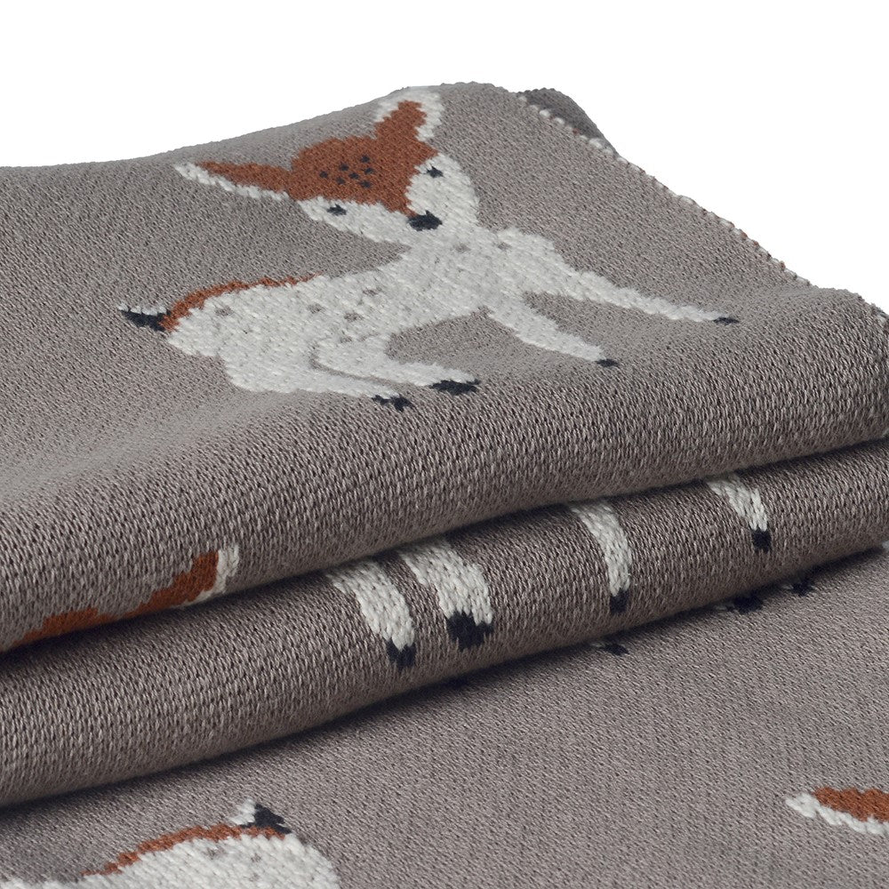 Close up of folded neutral Christmas throw with Bambi reindeer print.