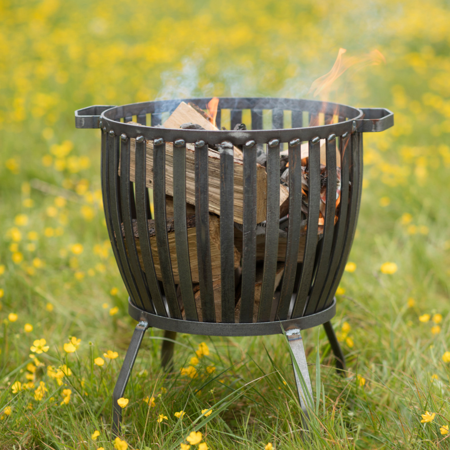 Fire pit basket lit on a field.