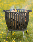 Fire pit basket lit on a field.