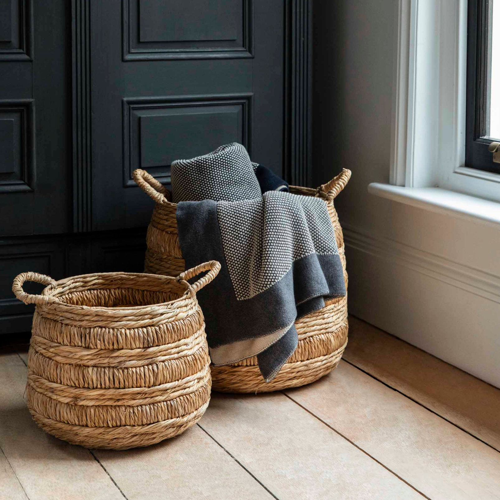 two storage baskets in room with black wardrobe.