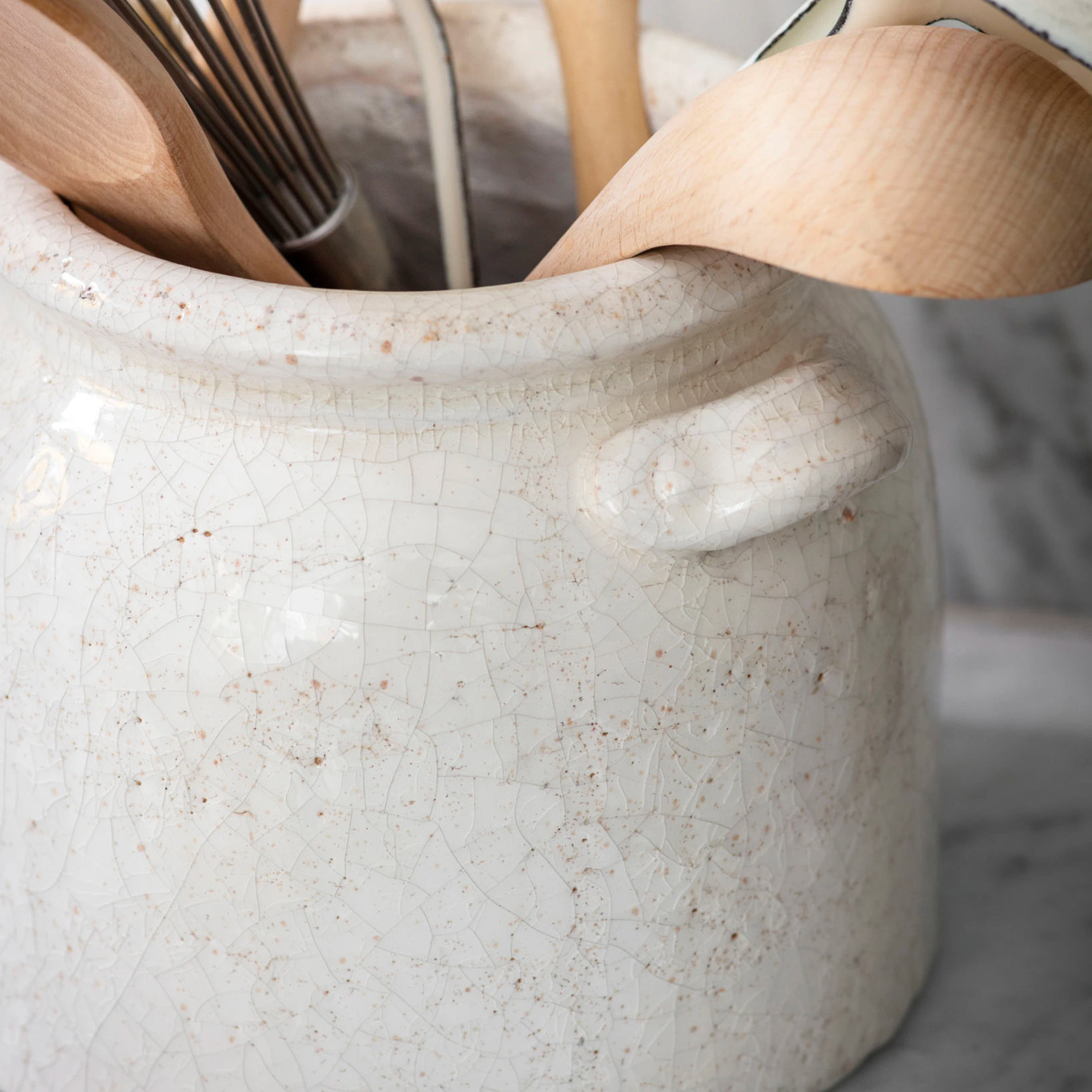 Detail shot of ceramic utensil holder with wooden utensils.