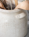 Detail shot of ceramic utensil holder with wooden utensils.