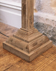 Close up of white washed wooden floor lamp base on wooden floor.