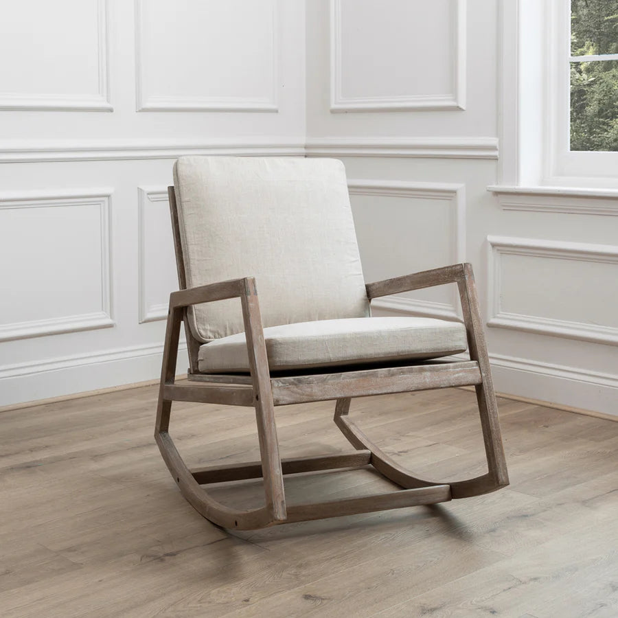 Mango wood rocking chair with natural plush cushions in the corner of an empty room.