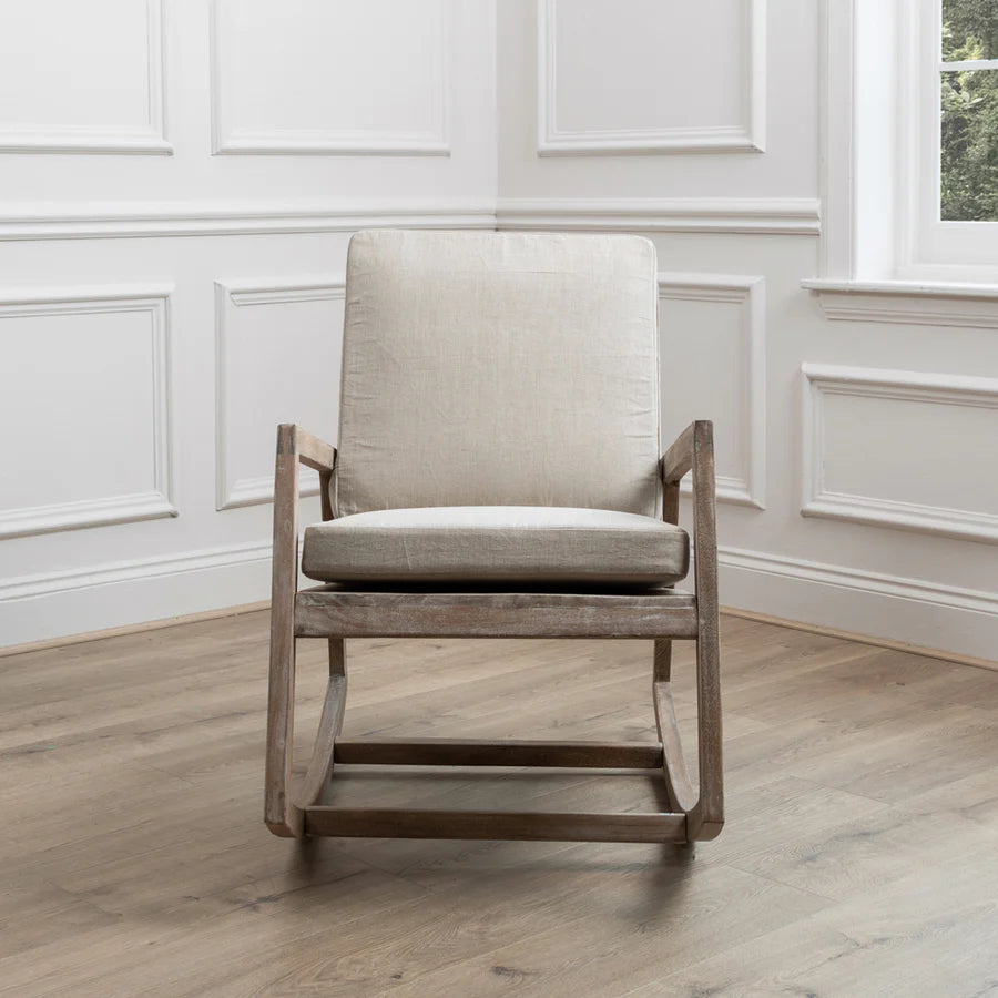 Mango wood rocking chair with natural plush cushions from the front view, in the corner of an empty room.