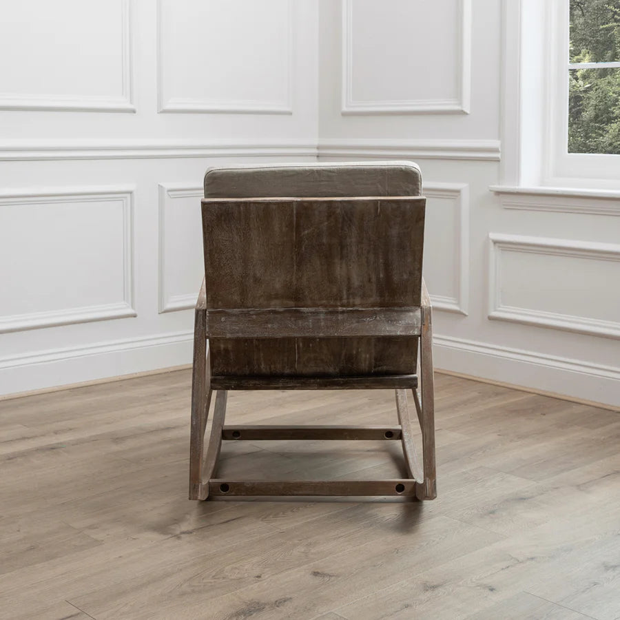 Mango wood rocking chair with natural plush cushions from the back view, in the corner of an empty room.