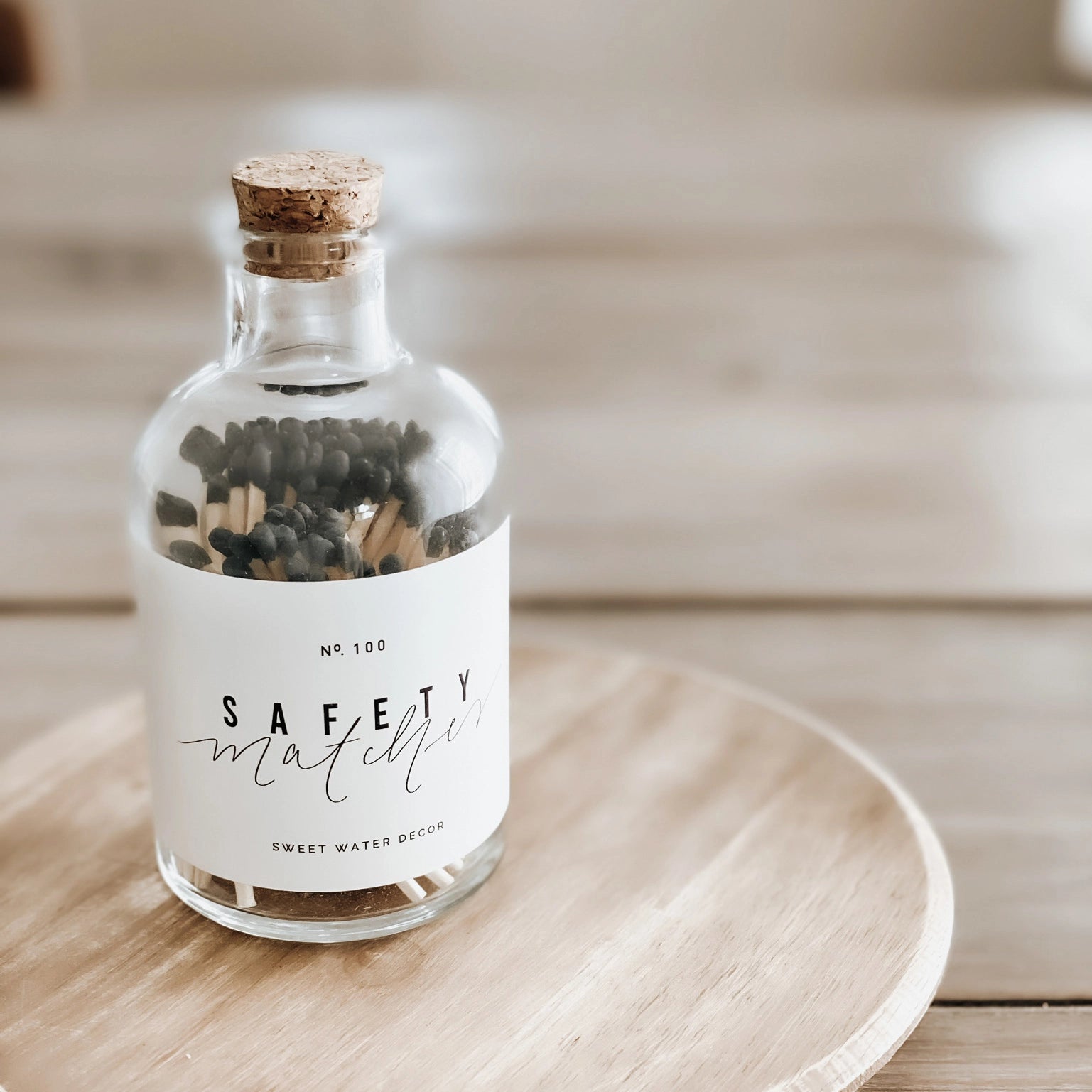 Black tipped matches in clear apothecary jar on wooden plank.