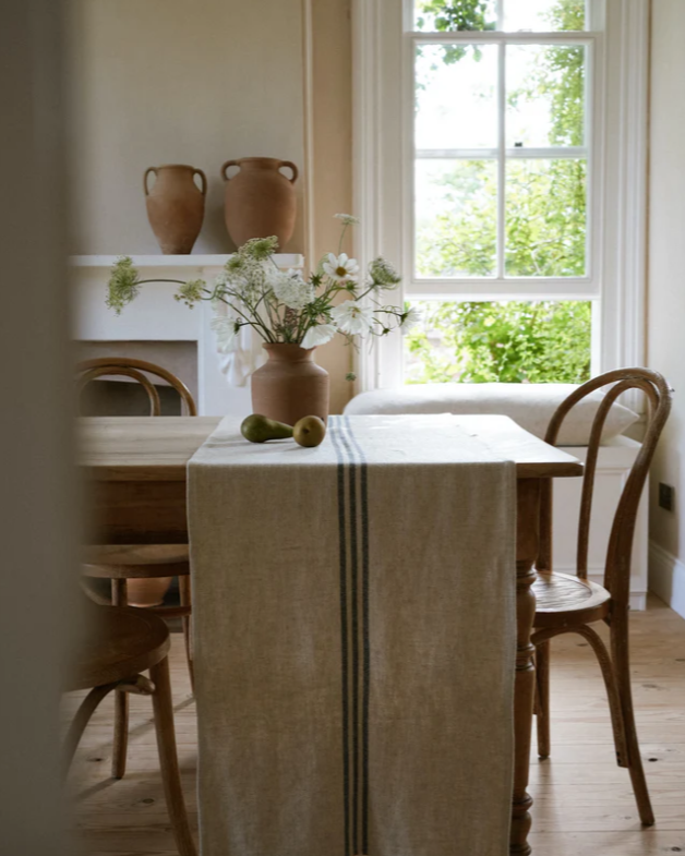 Cream and blue striped linen table runner, draped over wooden dining table.