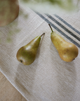 Close up of cream and blue striped linen table runner with two pears on top.