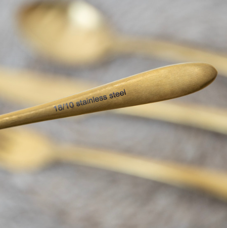 Close up of 18/10 stainless steel mark on brass cutlery set.