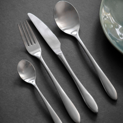 Silver cutlery set laid out with fork, spoon, knife and teaspoon.