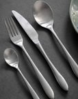 Silver cutlery set laid out with fork, spoon, knife and teaspoon.