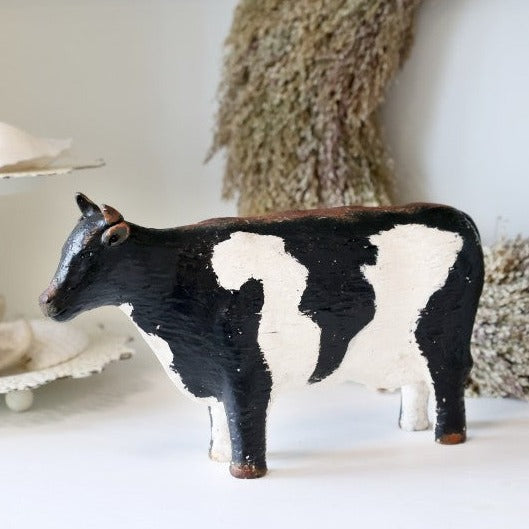 Painted cow ornament on white surface.