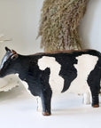 Painted cow ornament on white surface.