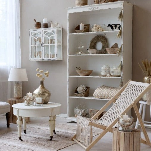 White bookcase filled with neutral coloured ornaments in living room.