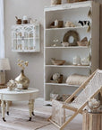 White bookcase filled with neutral coloured ornaments in living room.