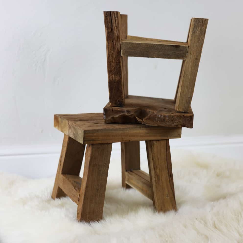 Two small wooden stools stacked atop of each other on a furry white rug. 