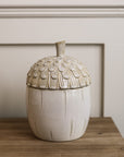 Ceramic off white acorn jar on wooden console table.