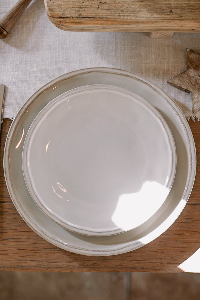 white ceramic dinner plate on wooden table with white table runner.