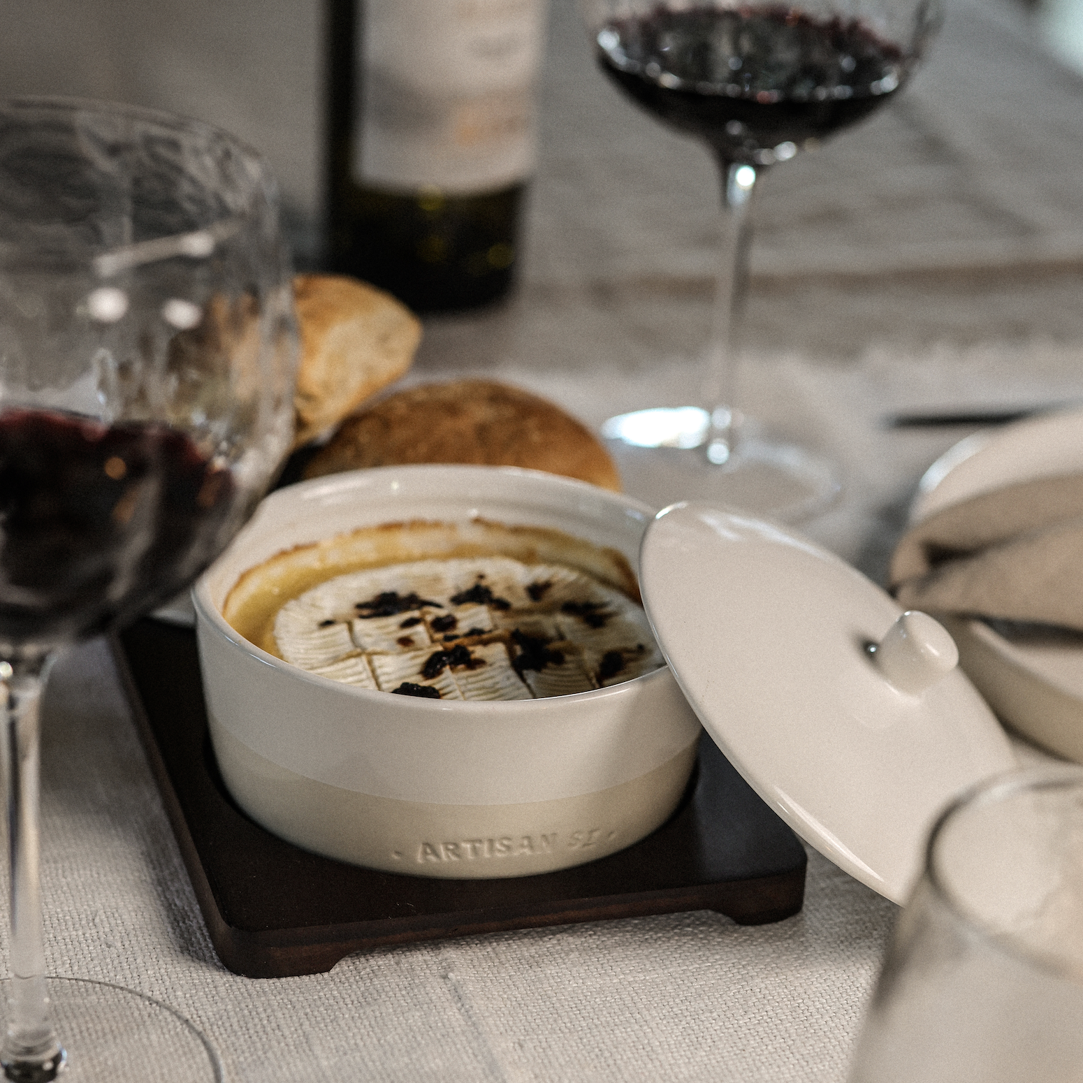 Cheese Baker set with cheese, chilli and wine on linen tablecloth.