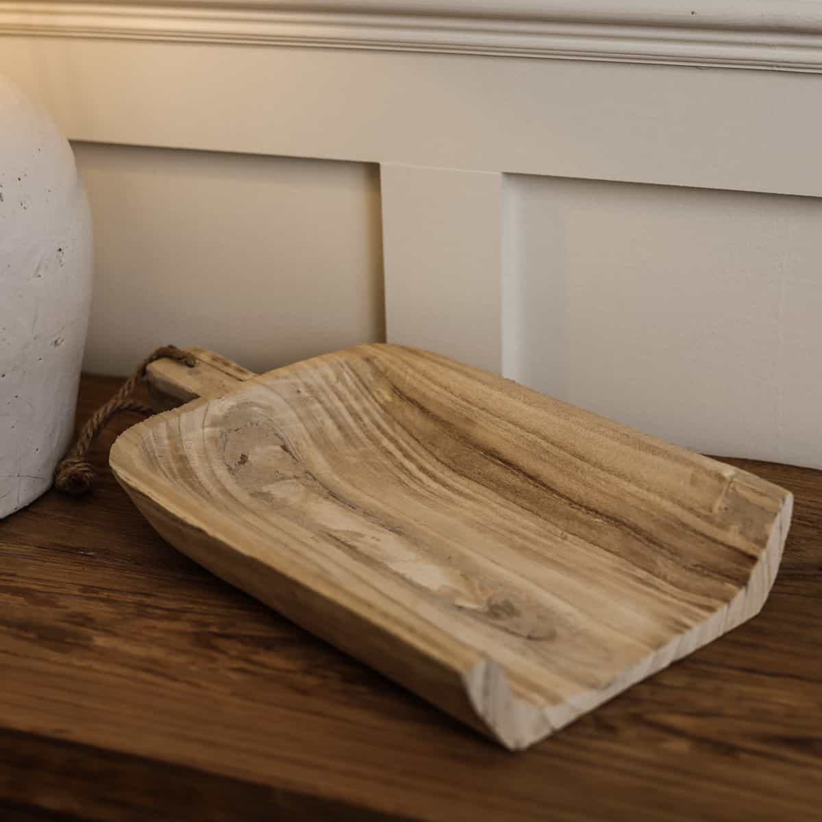 Wooden tray with rope on wooden console. 