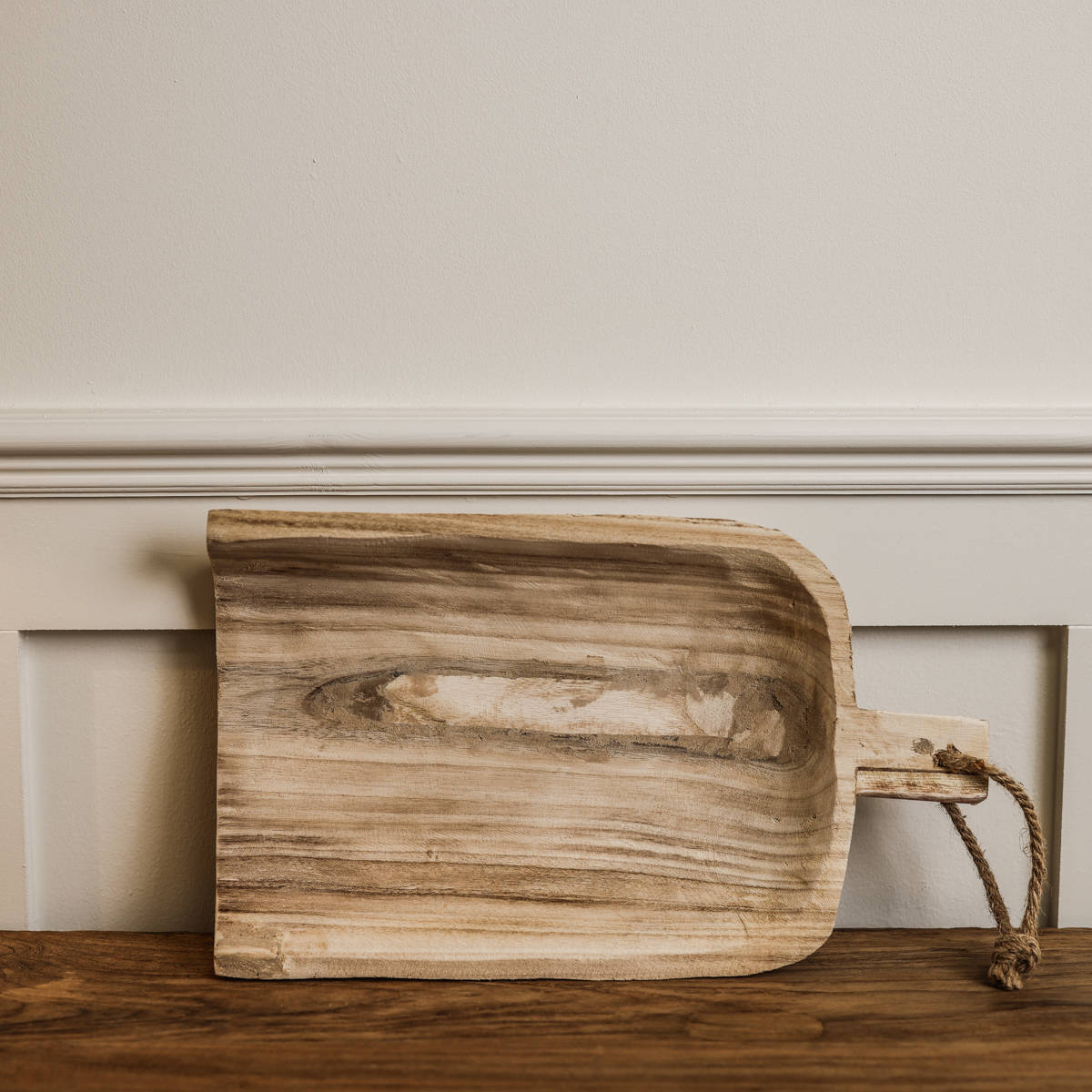 Wooden shovel tray on side against a wall.