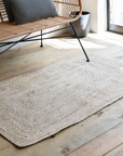 jute rug on wooden floor with metal and rattan bench.