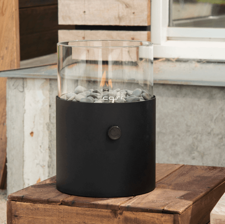 Black outdoor lantern, lit on a wooden table.