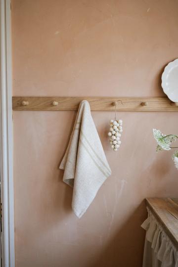 Cream striped kitchen towel hanging from a wooden hook.