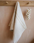 Cream striped kitchen towel hanging from a wooden hook.