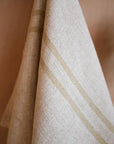 Close up of cream striped kitchen towel hanging from a wooden hook.