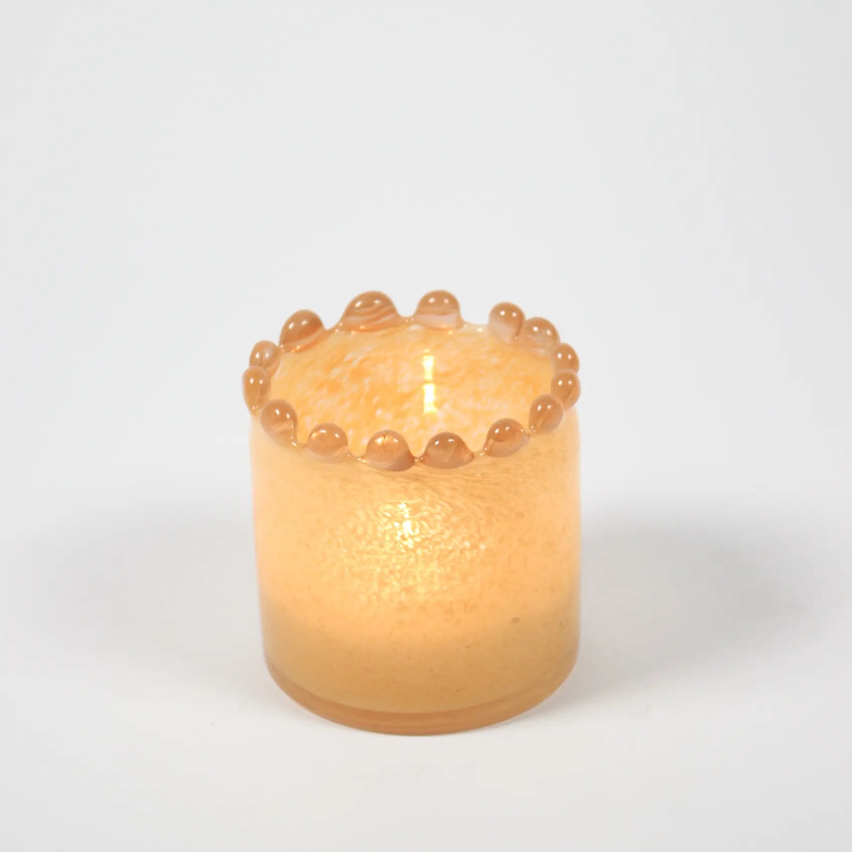 Glass candle holder with lit candle inside. 