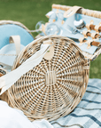 Close up of round picnic basket open on checked picnic basket. 