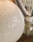Close up of glazed textured white ceramic table lamp.