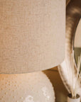 Close up of white textured ceramic table lamp and shade.