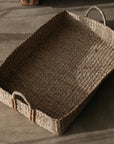 The large Eliza Rectangular Seagrass Basket on a concrete floor.