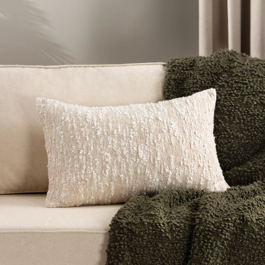 Rustic woven bouclé rectangle natural cushion on sofa with green throw.