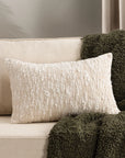 Rustic woven bouclé rectangle natural cushion on sofa with green throw.